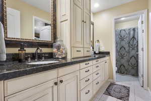 Full bath featuring tile patterned flooring, vanity, toilet, a shower with shower curtain, and baseboards