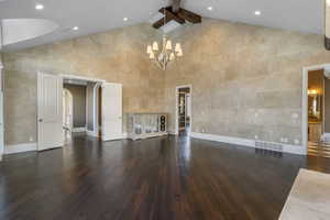 Unfurnished living room with baseboards, a notable chandelier, high vaulted ceiling, and hardwood / wood-style flooring