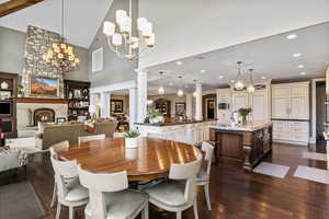 Dining space featuring dark wood-type flooring, a fireplace, a chandelier, and high vaulted ceiling