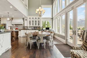 Dining space featuring baseboards, dark wood finished floors, an inviting chandelier, and a towering ceiling