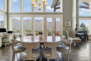 Dining space featuring a chandelier, plenty of natural light, dark wood-type flooring, and a towering ceiling