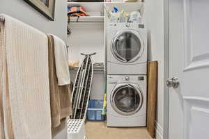 Laundry area featuring stacked washer and dryer, laundry area, and carpet