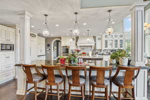 Kitchen with appliances with stainless steel finishes, tasteful backsplash, a large island with sink, custom range hood, and recessed lighting
