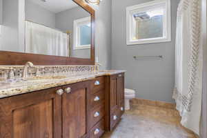 Full bath featuring double vanity, baseboards, a sink, and a wealth of natural light