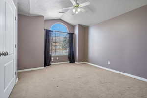 Unfurnished bedroom with a textured ceiling, carpet, baseboards, vaulted ceiling, and visible vents