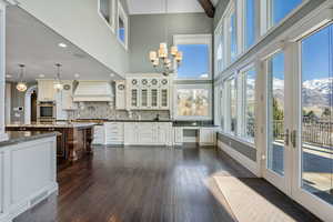 Interior space with custom range hood, a chandelier, dark wood-style floors, and light stone counters