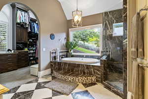 Bathroom with a chandelier, a marble finish shower, baseboards, vaulted ceiling, and a garden tub