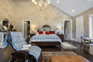 Bedroom with high vaulted ceiling, baseboards, hardwood / wood-style flooring, and a chandelier