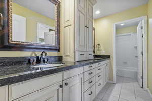 Full bath with double vanity, tile patterned flooring, a sink, baseboards, and a tub to relax in