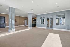 Exercise room featuring ornate columns, crown molding, and light carpet