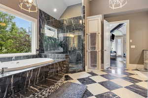 Full bath with an inviting chandelier, lofted ceiling, baseboards, a bath, and a marble finish shower