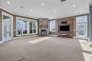 Unfurnished living room with crown molding, plenty of natural light, light carpet, and recessed lighting