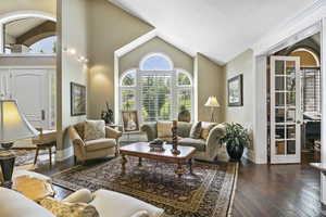 Living room with baseboards, dark wood-style floors, and lofted ceiling