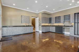 Kitchen featuring dark countertops, open shelves, baseboards, visible vents, and ornamental molding