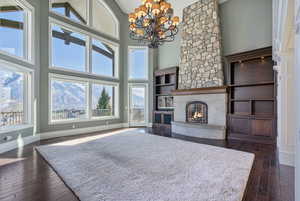 Living area with a high ceiling, a notable chandelier, a premium fireplace, baseboards, and dark wood-style floors