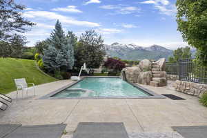 View of pool with fence, a mountain view, a pool with connected hot tub, and a patio area