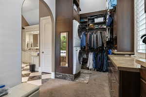 Walk in closet featuring arched walkways, stacked washer / dryer, and lofted ceiling