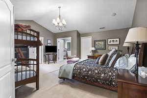 Bedroom with visible vents, lofted ceiling, light colored carpet, a textured ceiling, and a chandelier