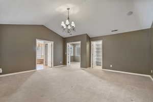 Empty room featuring visible vents, baseboards, a chandelier, and light carpet