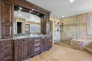 Bathroom with a sink, double vanity, a shower stall, and a textured ceiling