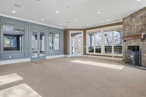 Unfurnished living room featuring french doors, crown molding, a fireplace, carpet floors, and recessed lighting