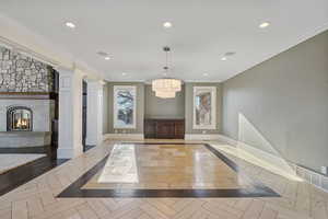Interior space featuring a stone fireplace, recessed lighting, ornate columns, and an inviting chandelier