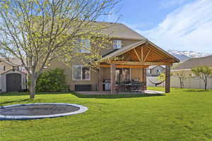 Back of house featuring a storage shed, a patio area, a trampoline, and large yard