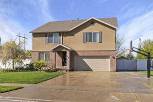 View of front of home with fence, a front yard, stucco siding, an attached garage, and driveway