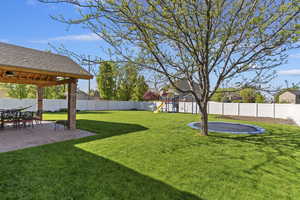 View of yard featuring a fenced backyard, a patio, and in-ground trampoline