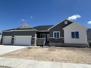 View of front of home featuring board and batten siding, a porch, driveway, an attached garage, and stone siding