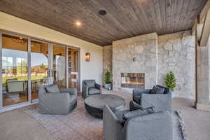 Living area featuring an outdoor stone fireplace, wood ceiling, carpet, and french doors