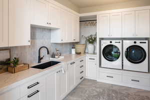 Washroom with cabinet space, a sink, and washer and dryer