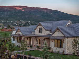 View of front of home with a standing seam roof, a mountain view, metal roof, and stone siding