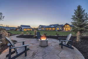Patio terrace at dusk featuring a lawn and a fire pit