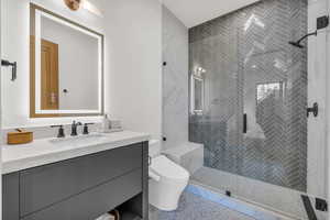 Full bathroom featuring vanity, a stall shower, and toilet