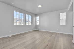 Spare room featuring light wood-style floors, baseboards, and visible vents
