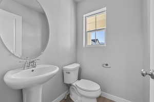 Bathroom featuring toilet, baseboards, a sink, and wood finished floors