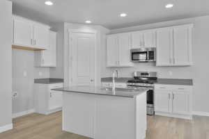 Kitchen featuring baseboards, a sink, light wood-style flooring, and appliances with stainless steel finishes