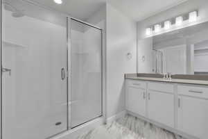 Full bathroom featuring vanity, baseboards, a shower stall, and marble finish floor