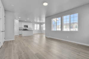 Unfurnished living room with recessed lighting, baseboards, and light wood-style flooring