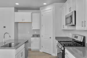 Kitchen with a sink, white cabinets, stainless steel appliances, and recessed lighting