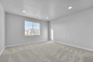 Carpeted empty room with recessed lighting, a textured ceiling, and visible vents