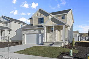 Traditional home with board and batten siding, concrete driveway, stone siding, and a garage