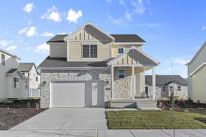 View of front of property with a garage, stone siding, board and batten siding, a porch, and driveway