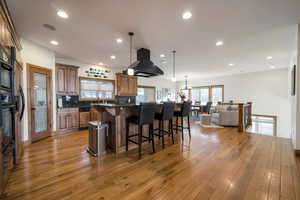 Kitchen with brown cabinets, dark countertops, a breakfast bar area, light wood-style flooring, and open floor plan