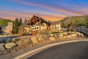 View of front of property featuring fence, a mountain view, stairs, stone siding, and stucco siding