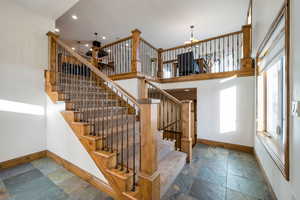 Stairs featuring an inviting chandelier, baseboards, recessed lighting, and stone tile floors