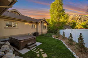 Yard at dusk featuring a hot tub, central AC unit, and a fenced backyard