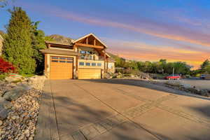 View of front of property with fence, stone siding, stucco siding, concrete driveway, and a balcony