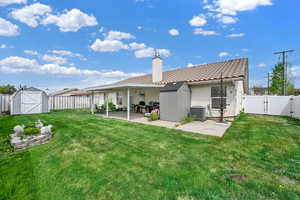 Back of house with a storage shed, a fenced backyard, a gate, a chimney, and a patio